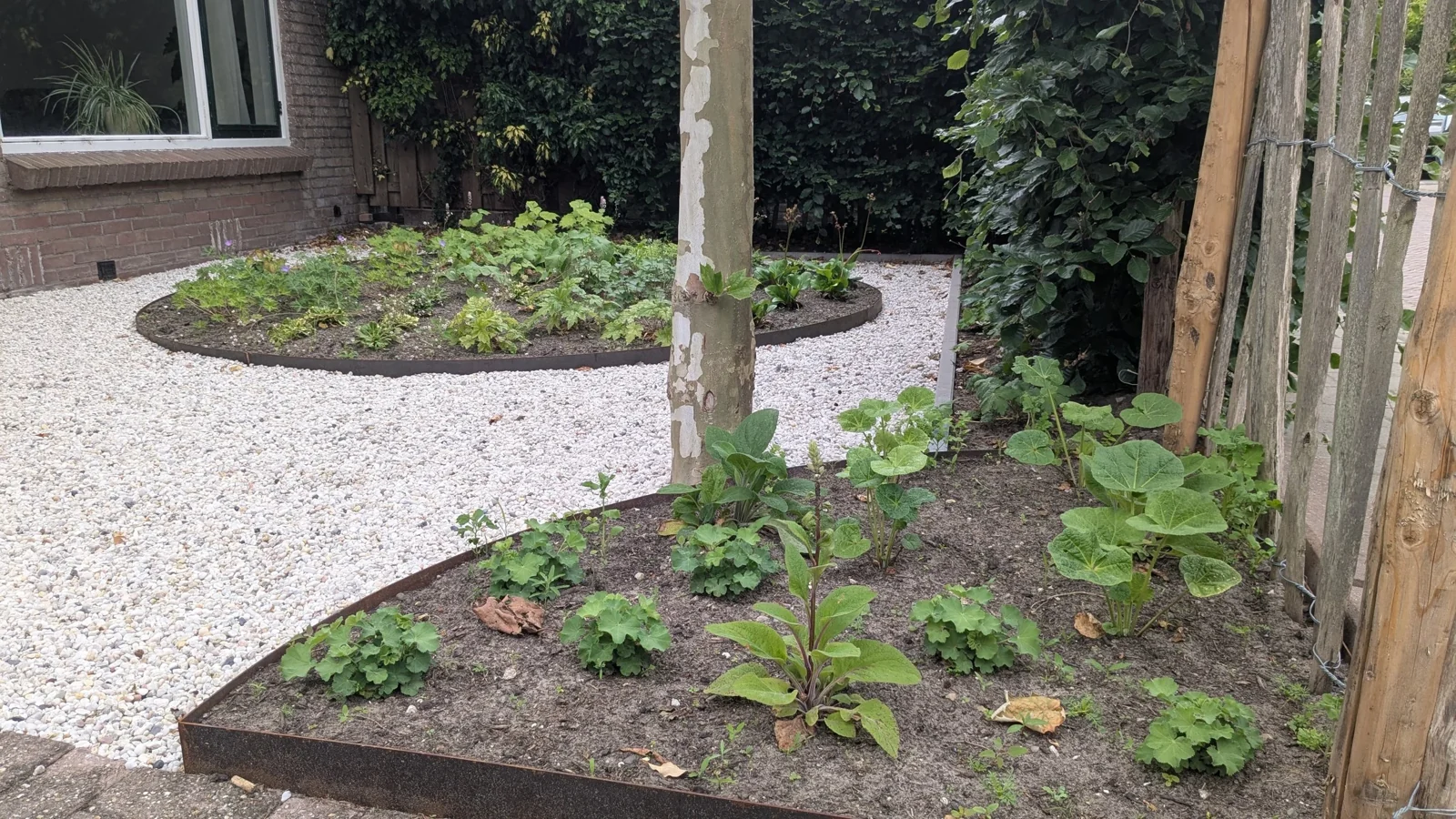 Ronde borders met een cortenstalen rand en licht grind in een voortuin in De Bilt