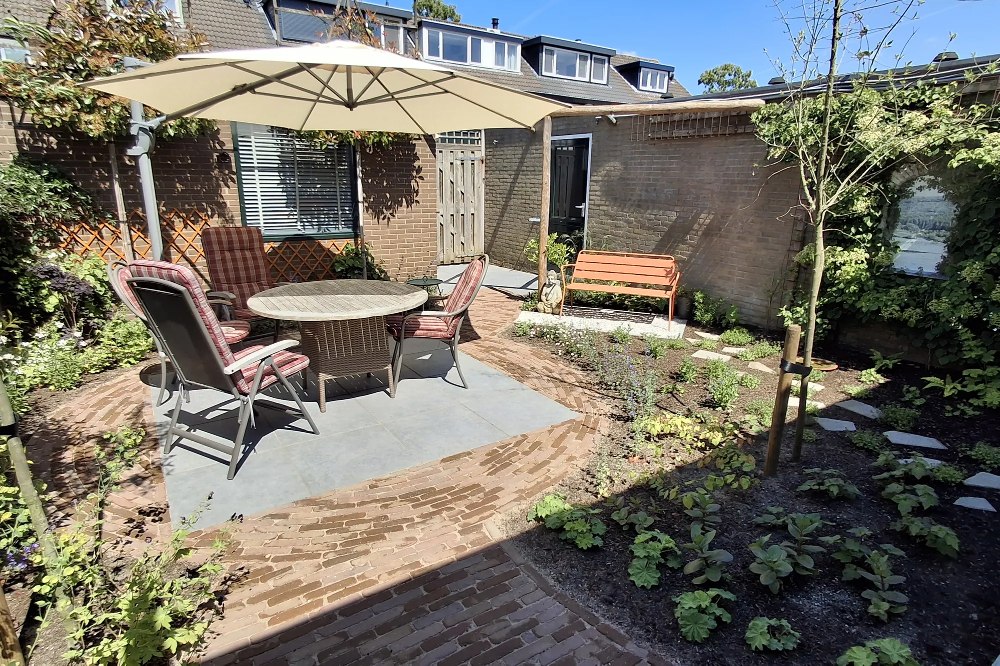 Rond terras met tafel en parasol tussen jonge borders in De Bilt