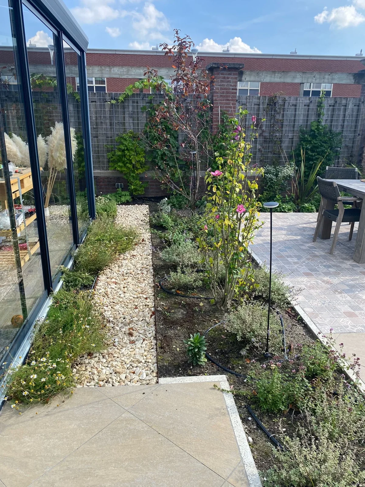 Grindpad langs een border bij de serre in een mediterrane tuin in Hoofddorp